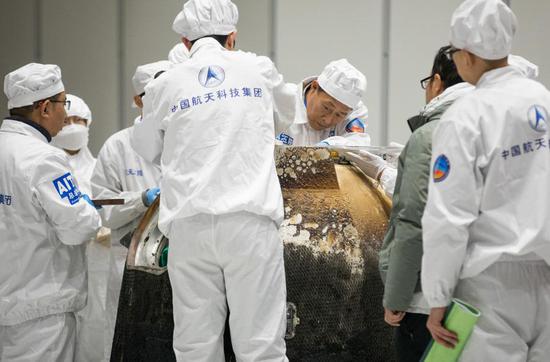 　2020年12月17日，在中国航天科技集团五院，科研人员打开嫦娥五号返回器舱门，取出装有月球样品的容器并进行称重。新华社记者 金立旺 摄