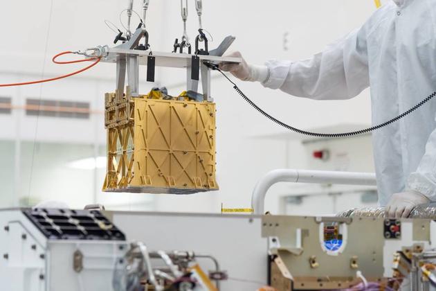 美国宇航局喷气推进实验室的技术人员将火星氧气原位资源利用实验（MOXIE）仪器放入毅力号火星车腹部。